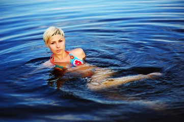 Blond girl swimming in crystal-clear pool