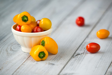 Naklejka na ściany i meble Colored cherry tomatoes and mini paprika in a bowl on a wooden t
