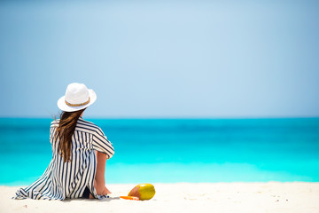 Fototapeta na wymiar Young woman on white beach with coconut