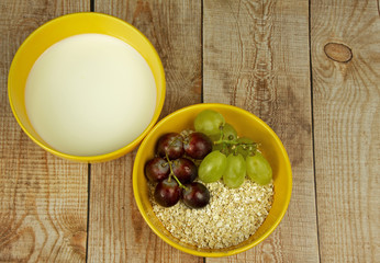 Oatmeal with grapes and milk on a wooden countertop