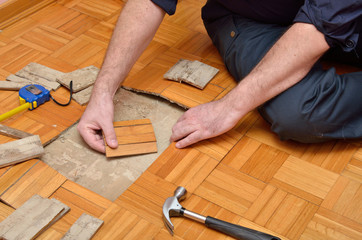 Worker Repairing Damaged Parquet in Apartment