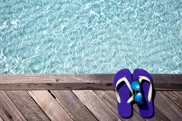Flip Flops mit Sonnenbrille auf einem Holzsteg