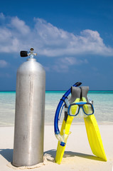 Taucherflasche mit Taucherbrille und Flossen am Strand