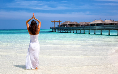 Frau parktiziert Yoga am Strand der Malediven