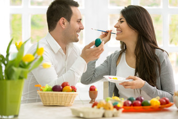 Couple having fun while painting eggs