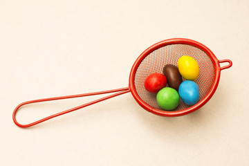 Red strainer with colorful candy, close-up