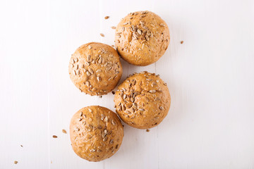 Four buns with seeds on a light wooden background, top view 