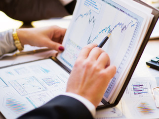 Close-up of female and male hands pointing at business document while discussing it