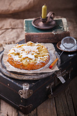 Apple cake on a vintage suitcase in powdered sugar.selective focus.