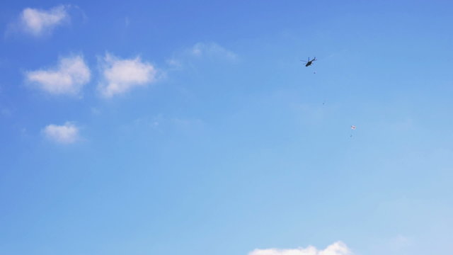 Military paratroopers jump out of a helicopter