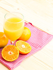 Glass of orange juice with orange slice on soft wooden background