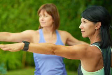 Fototapeta premium Two mature women keeping fit by doing yoga in the summer