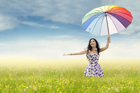 Woman with colorful umbrella on meadow