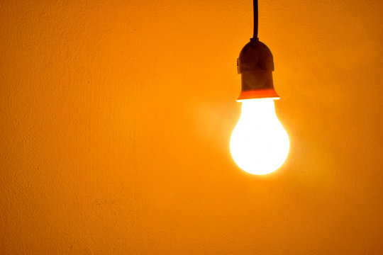 Incandescent light bulb orange light on wall