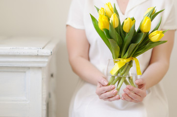 Yellow, fresh tulips in the hands of a beautiful woman.