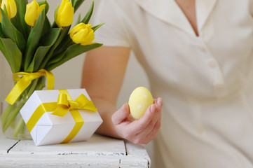 Beautiful woman with a gift and fresh yellow tulips. Easter.