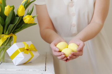 Beautiful woman with a gift and fresh yellow tulips. Easter.