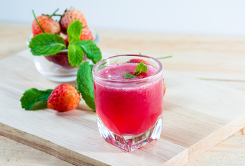 Fresh red strawberries juice in transparent glass for drink on w