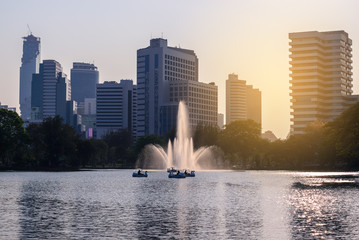 Bangkok skyline with urban lake and fountain in summer.