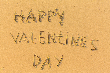 Happy Valentines Day - text written on sandy beach.