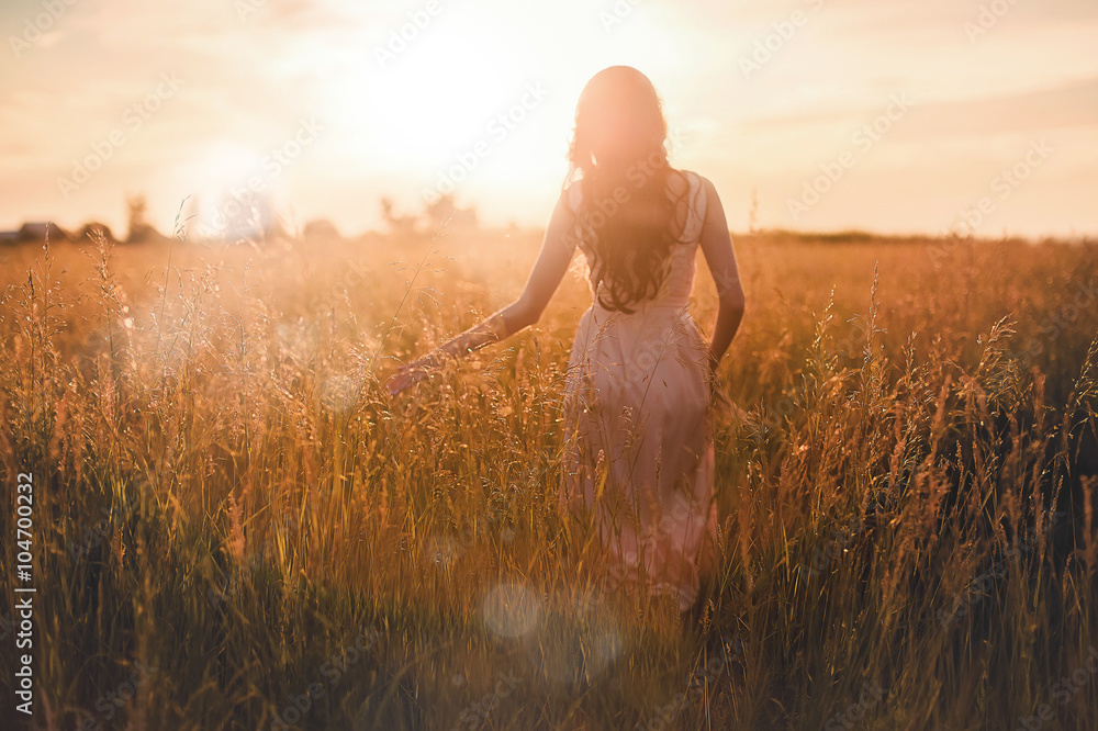 Wall mural she goes through the ears on the sunset viewed from behind