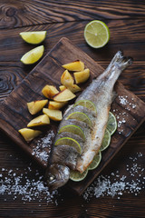 Baked trout fish with lime and potato in a rustic wooden setting