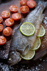 Close-up of baked trout fish with lime, sea salt and tomatoes