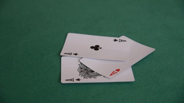 A hand of a woman throwing four aces one by one on the green cloth