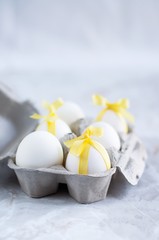 portauovo con uova bianche legate con nastrini gialli © faustalavagna