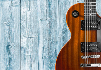 Part of the orange electric guitar on wooden background. A place for writing of the text.