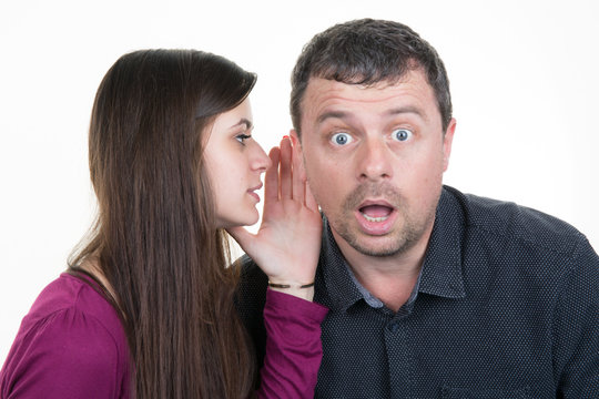 Woman whispering secret into a man friends ear