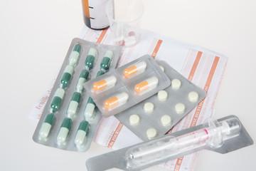 Prescription form lying on table with pills and syringes