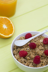 Granola in a bowl with raspberries and orange juice, muesli