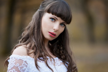 beautiful and happy smiling brunette bride in white lacy satin dress european style autumn background