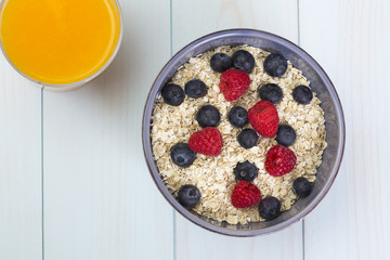 Rolled oats (oat flakes) in a bowl with milk, raspberries and bl