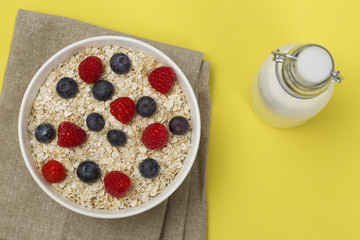 Rolled oats (oat flakes) in a bowl with raspberries, blueberries