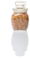 reakfast cereal with dried raspberry fruit pieces in glass jar over white background