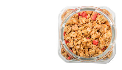 reakfast cereal with dried raspberry fruit pieces in glass jar over white background