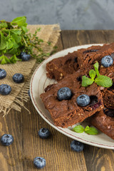 Chocolate brownie with peanuts, blueberries,mint on a wooden 
