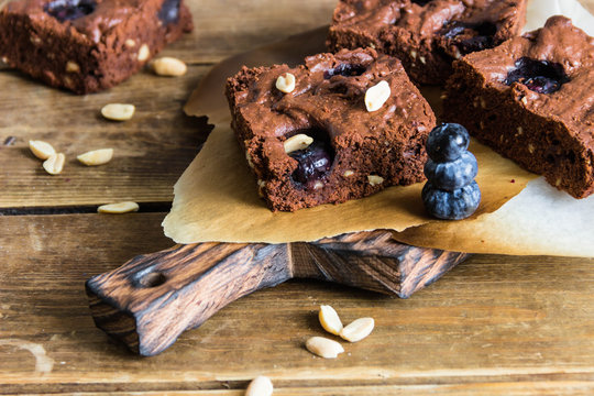 Chocolate brownie with peanuts,blueberries and mint on a wooden serving Board 