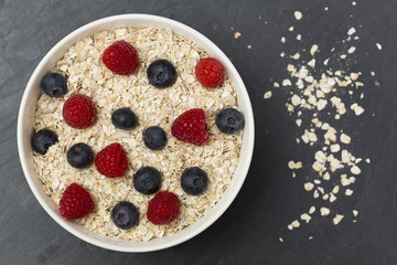 Rolled oats (oat flakes) in a bowl with raspberries, blueberries