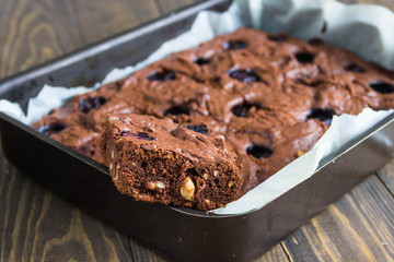 Chocolate brownie with blueberries in the baking pan on a wooden table