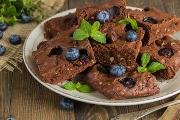 Chocolate brownie with peanuts, blueberries,mint on a wooden table  