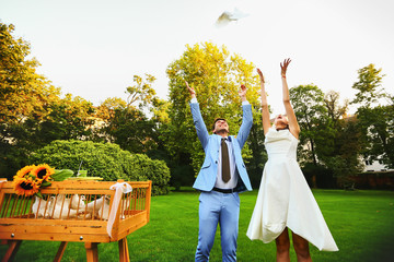 Happy smiling bride and groom hands releasing white doves on a s
