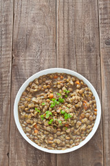 Draufsicht einer Linsensuppe im Teller auf einem Holztisch