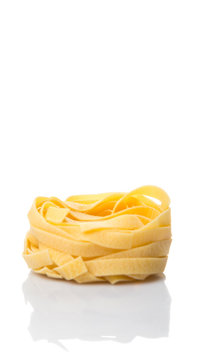 Dried tagliatelle pasta or ribbon shaped pasta or nest shape pasta over white background