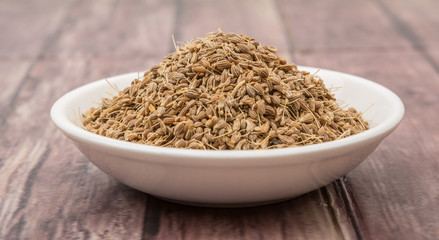 Dried aniseed in white bowl over wooden background