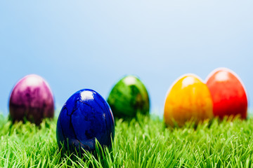 Unterschiedliche Oster Eier im Gras, blauer Hintergrund
