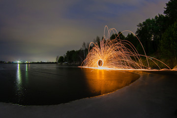 Sparks from the burning steel wool against the backdrop of a frozen lake spring night © meatbull