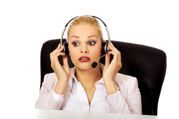 Young woman helpline operator is trying to hear something through a headphones